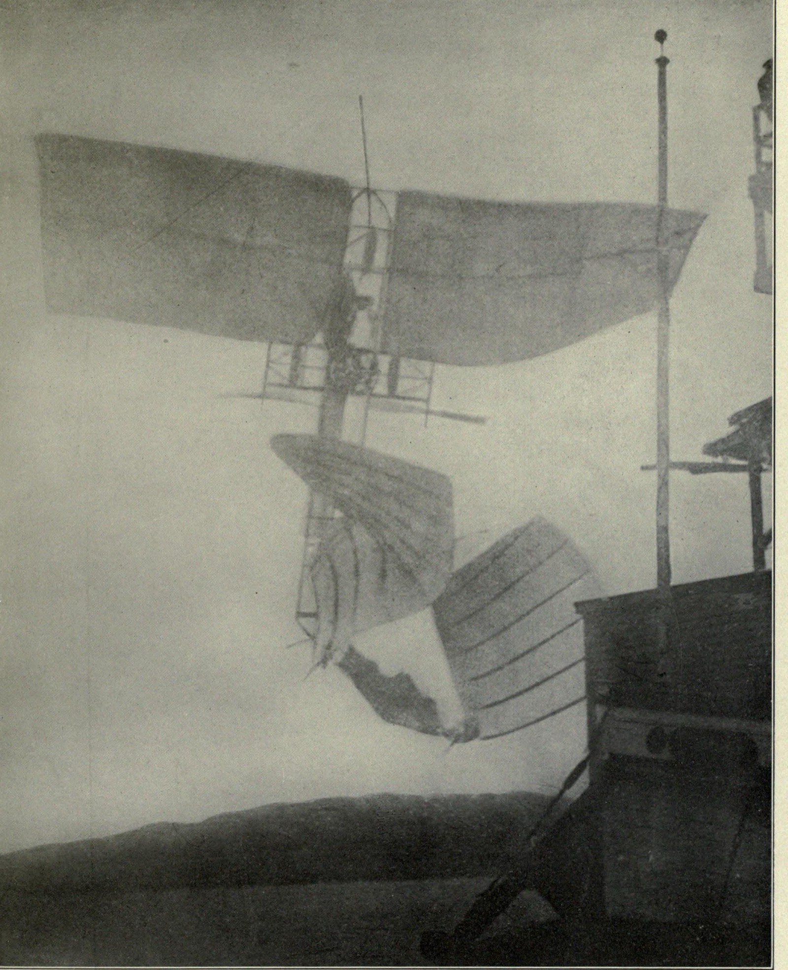 The Aerodrome standing almost vertical in the air beside the houseboat superstructure at dusk, its rear wings broken and folded and its front wings intact