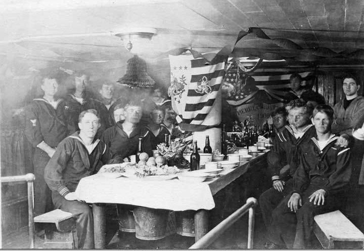 Sailors at a decorated table on the Bear's berth deck at Christmas dinner, 1909