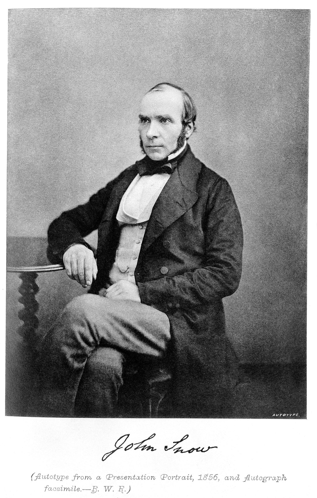 A seated photographic portrait of John Snow in a dark coat and bow tie, one arm resting on a table, with his signature reproduced beneath